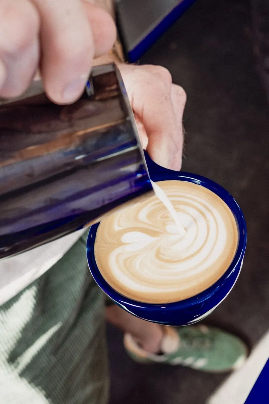Barista pouring milk into a flat white at the kiosk window