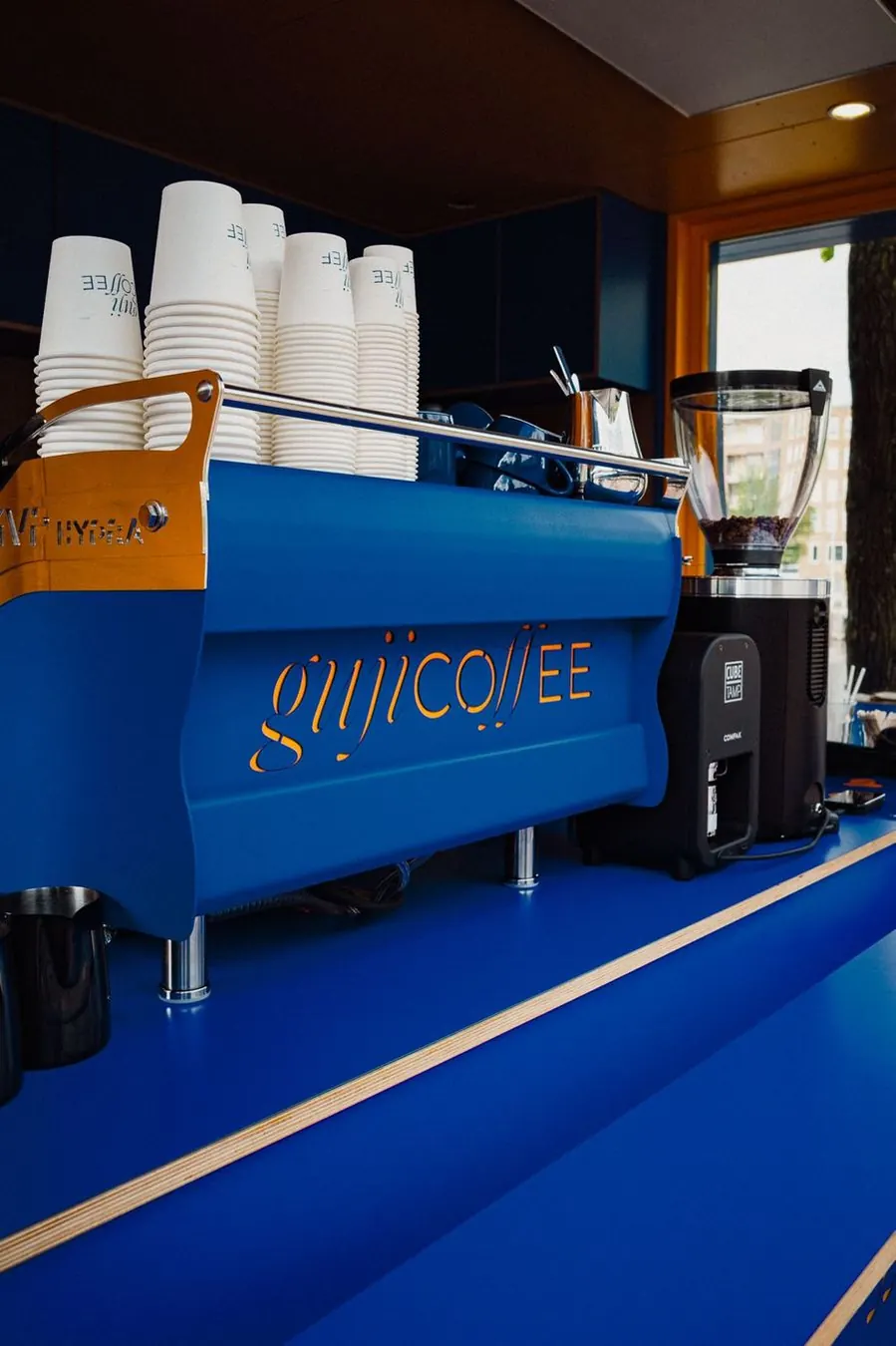 The blue bar of the kiosk with espresso machine and cups